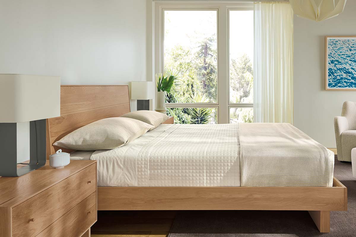 Hudson bed shown in bright bedroom with soft neutral bedding, wood nightstands, and floor-to-ceiling windows.
