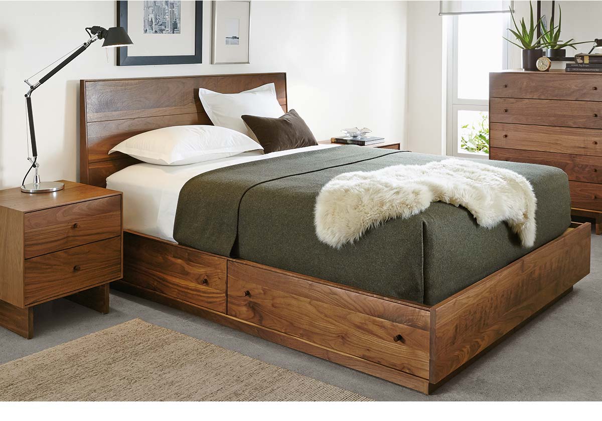 Hudson bed in walnut finish with green blanket and fur throw beside wood nightstand and lamp.