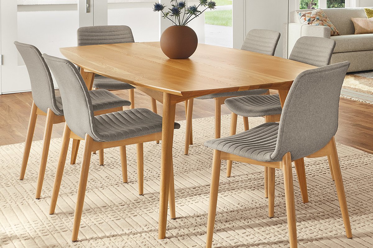 Ventura table shown with natural wood tones and grey Cato chairs on a textured ivory rug.