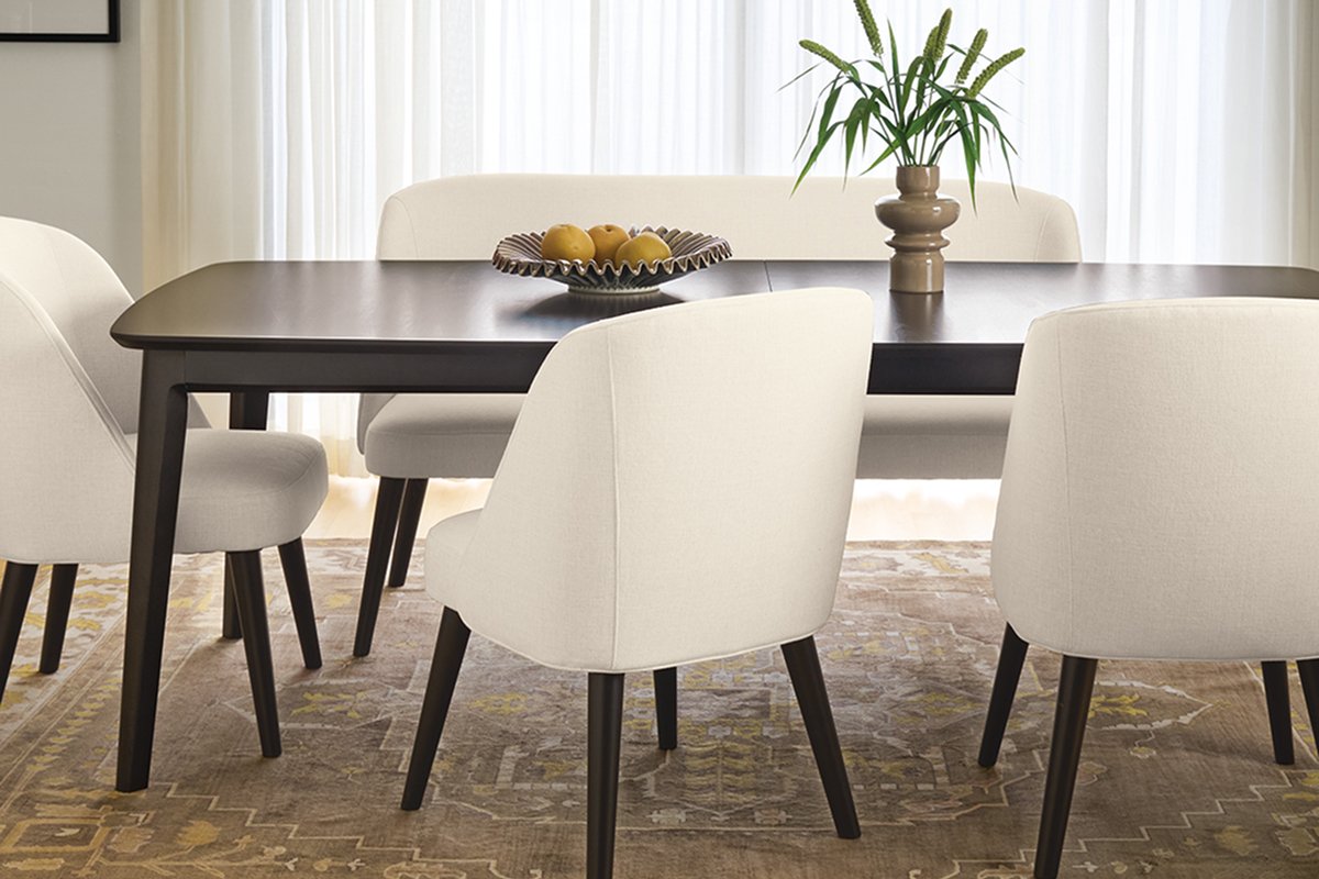 Cream-colored Cora chairs and bench paired with dark wood dining table and ceramic centerpiece.