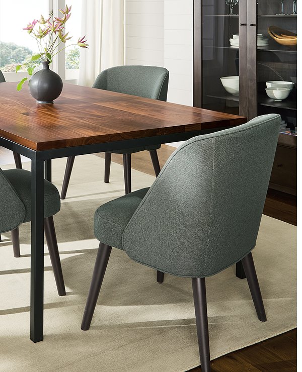 Green upholstered Cora chairs around rectangular wood table with dark metal legs.