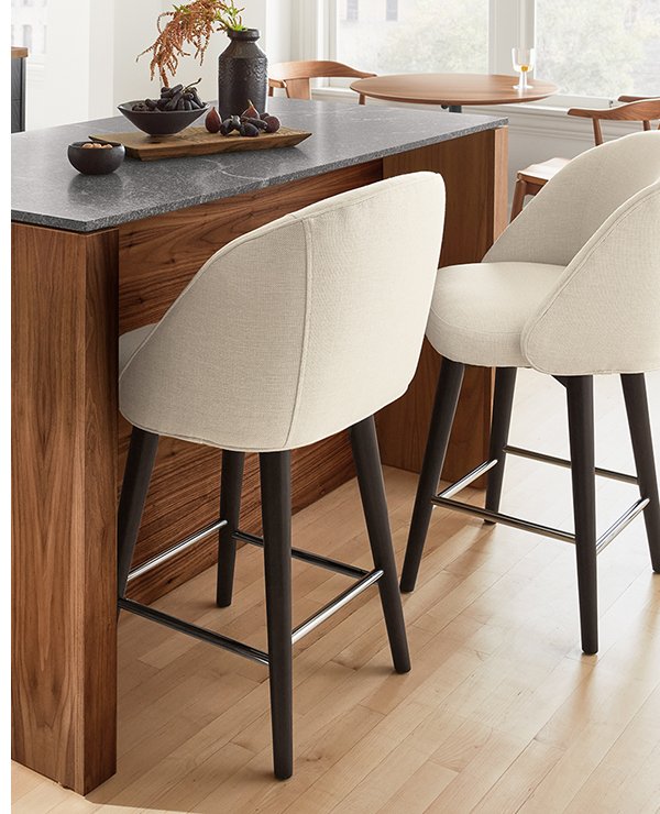 Cora counter stools in cream upholstery with dark wood legs at walnut kitchen island.