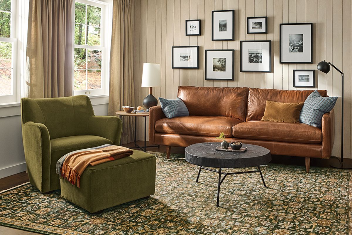 Rosalie rug in rich greens with vintage pattern, paired with leather Jasper sofa and green armchair.