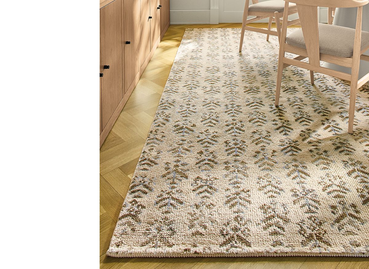 Beige and green patterened Leyla rug under a modern oak dining setup.