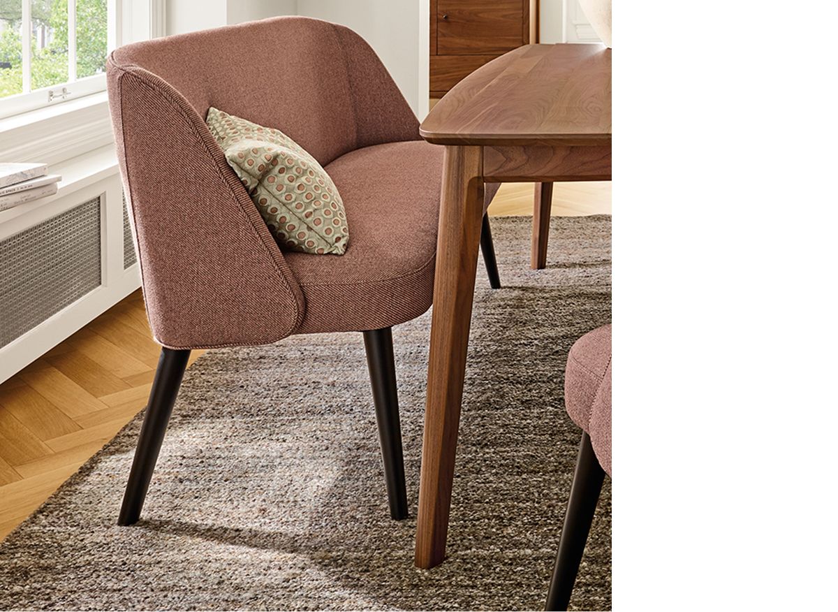 Grey textured Sefton rug under Walnut dining table and upholstered rust-colored Cora bench and chairs.