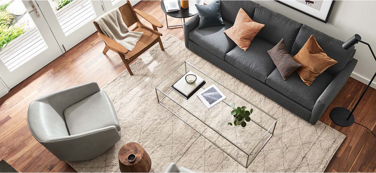 Textured Kalindi rug in ivory under modern seating and a clear glass-top coffee table.