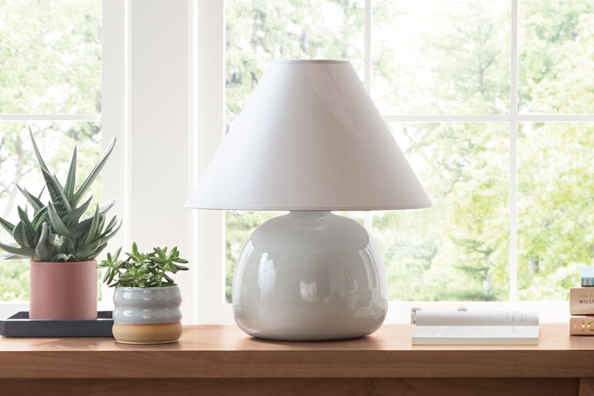 Glossy white Elsie table lamp centered on console, with books and decor.