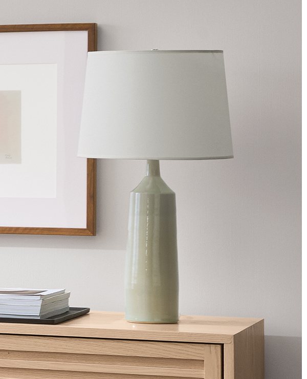 Light green Dupree table lamp on wood dresser beside a framed print.