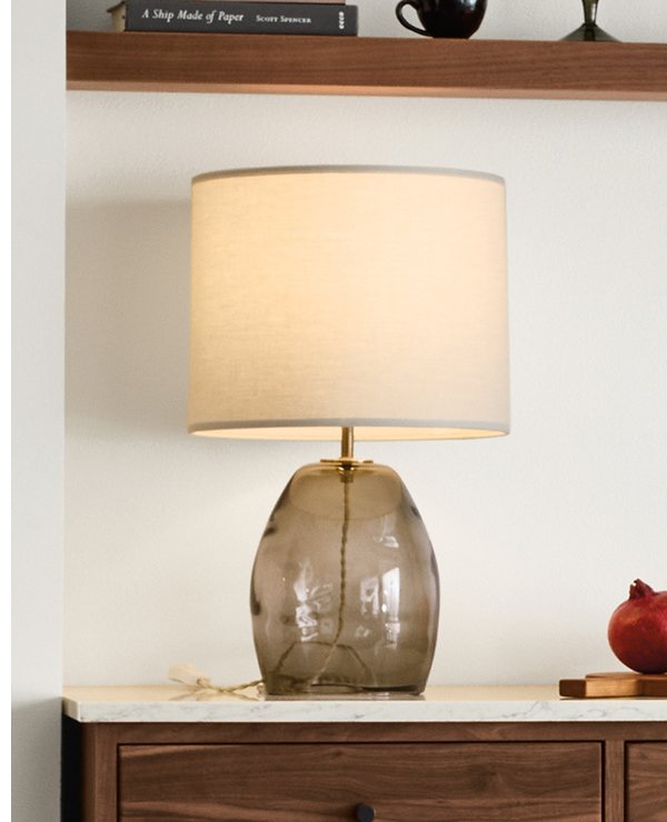 Grace table lamp on stone-topped cabinet with books and decor.
