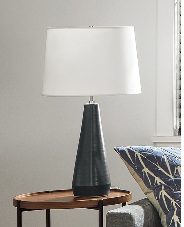 Tall tapered Donovan table lamp on a round wood side table.