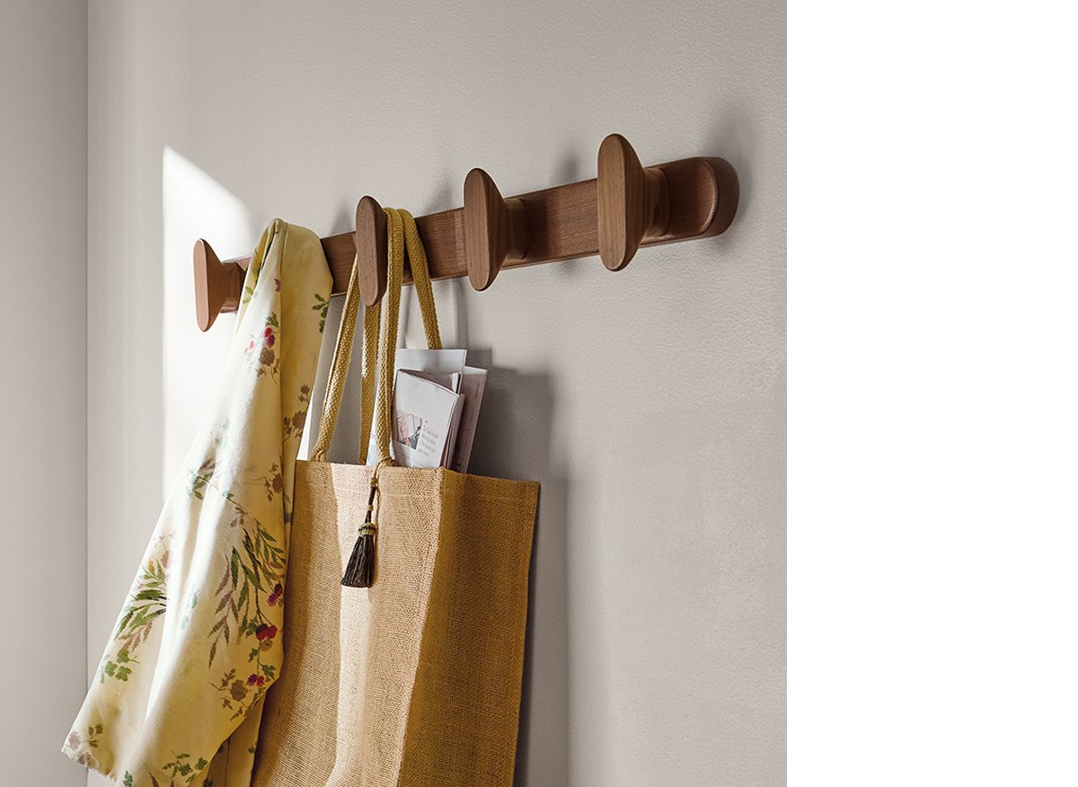 Sonora walnut wall hook rail with sculpted pegs, used to hang a tote and scarf.