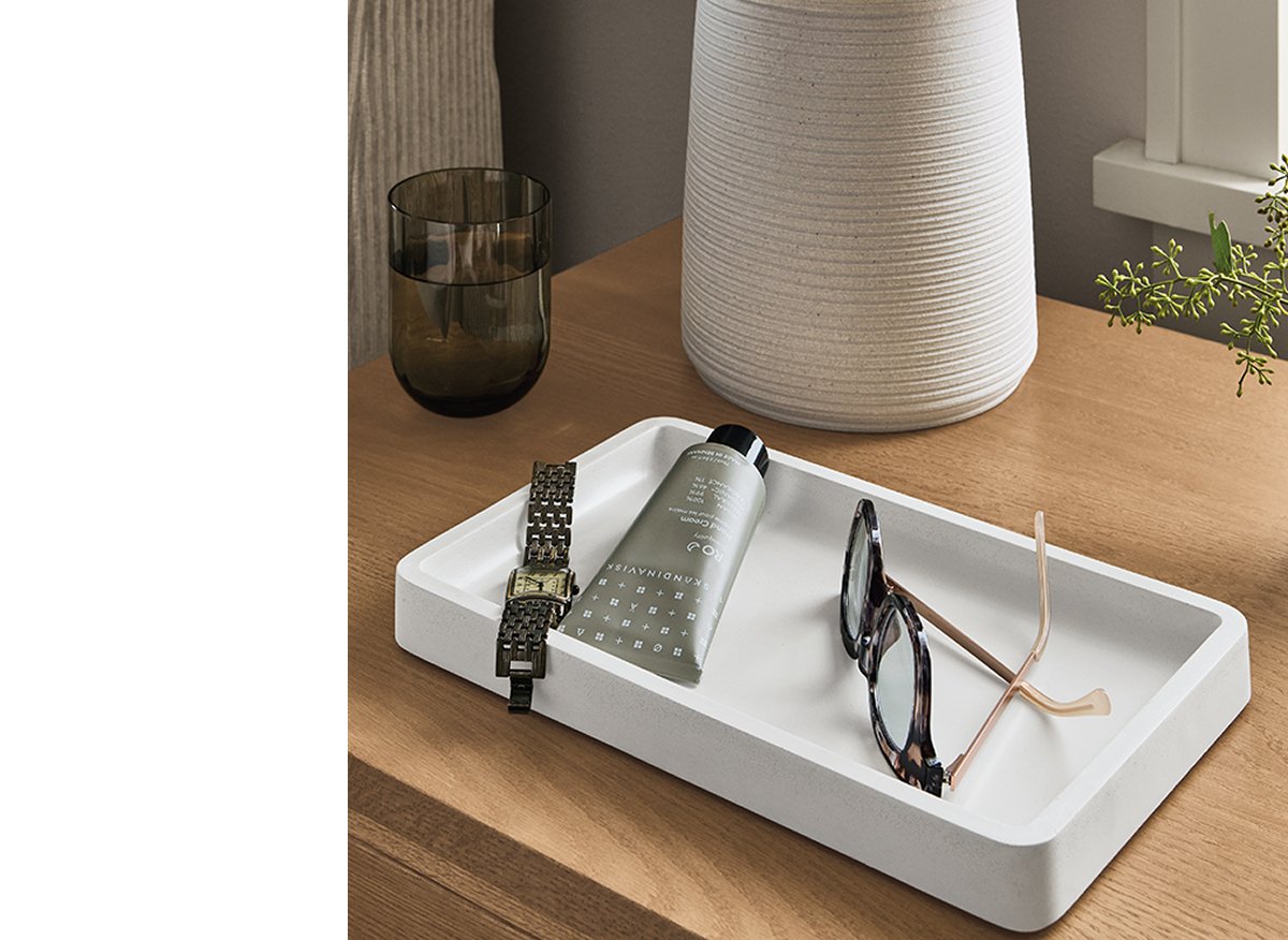 Matte white Kiser tray styled with eyewear and accessories beside lamp on wood dresser.