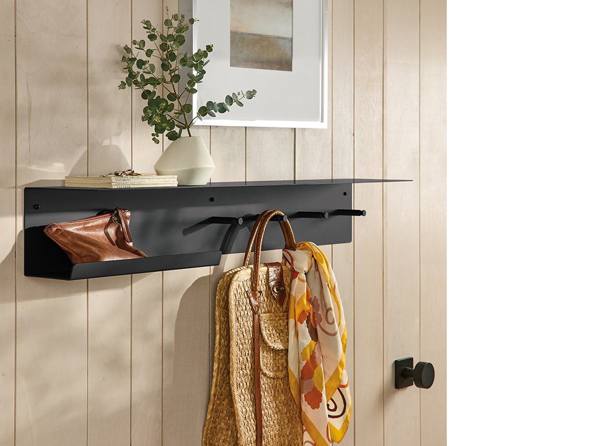 Black Spike metal wall shelf with hooks, mounted on wood panel wall with bags and decorative objects.
