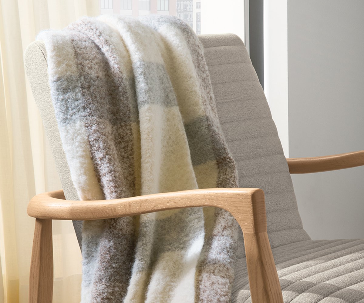 Beaumont throw with soft neutral check pattern draped over the back of a light upholstered Callan chair.