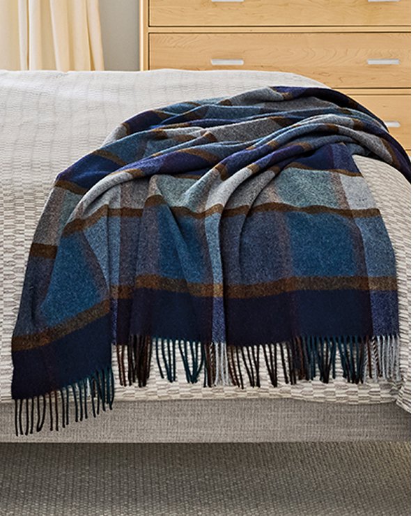 Irvine throw in navy and brown plaid folded at the foot of an Ella bed with light bedding.