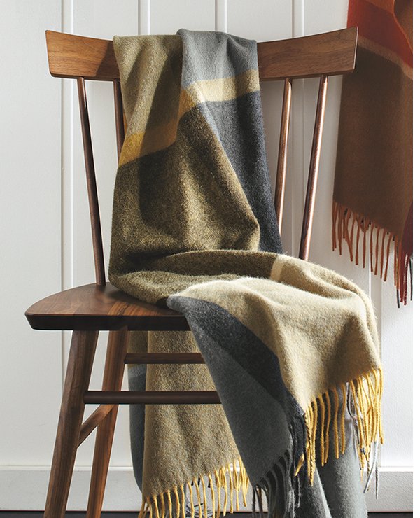 Horizon throw in green, gray, and tan blocks draped over a wood dining chair with spindle back.