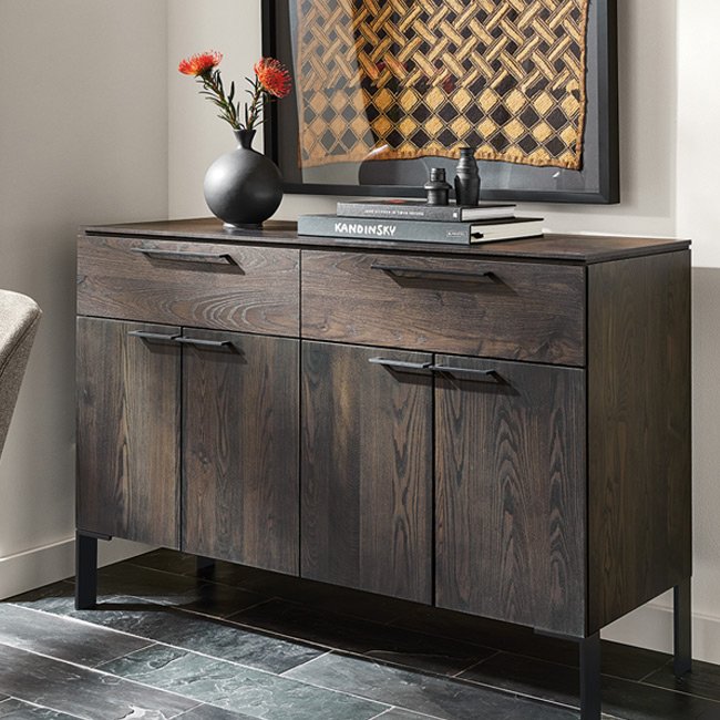 Dark wood Kenwood storage cabinet with metal legs, featuring decorative accents and books against a neutral wall.