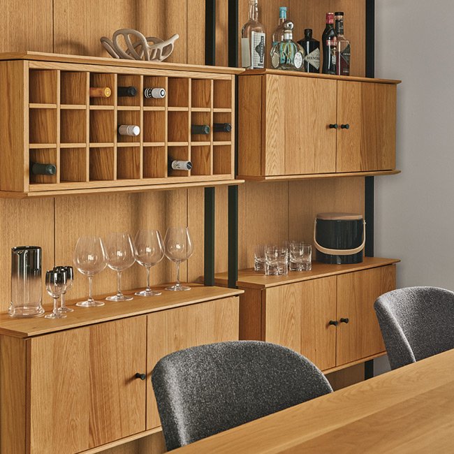 Beam bar cabinet with open shelves, closed storage, and a built-in wine rack, styled with bottles and glassware.