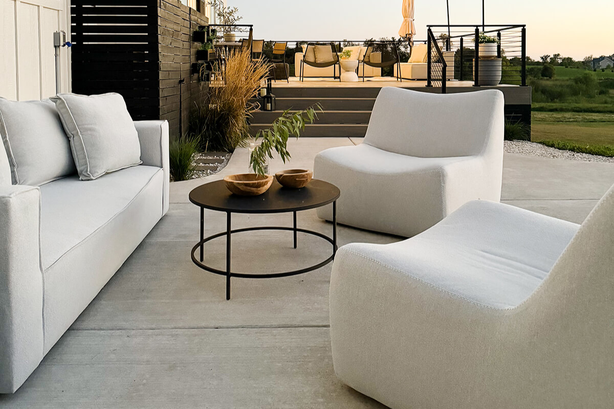 White Maya chairs arranged around a dining table on a patio, styled with dishes, glassware, and greenery.