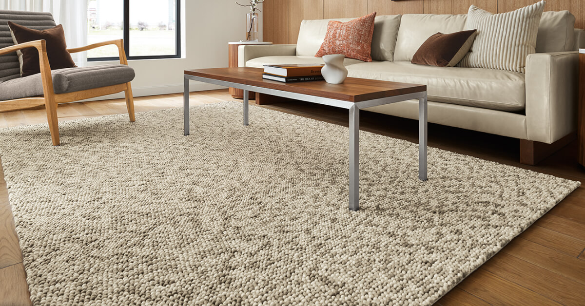 Hastings rug paired with Callan chair, sofa, and wood coffee table in living room with window and wood panel wall.