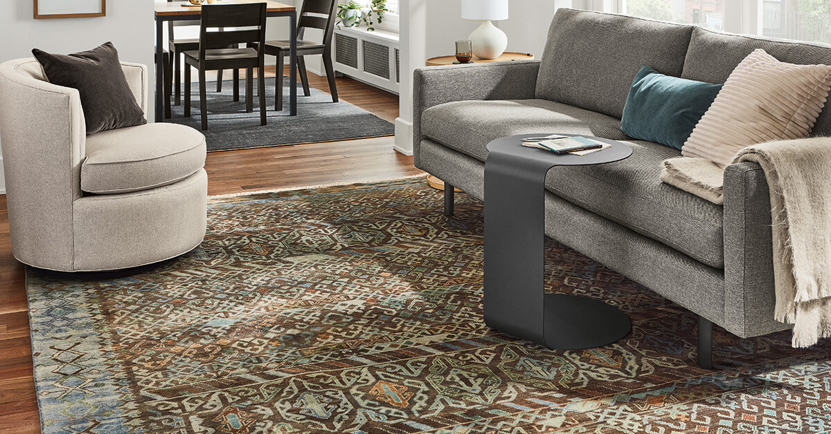 Jasper sofa with Timuri rug, black side table, and round chair in open living space with dining area behind.