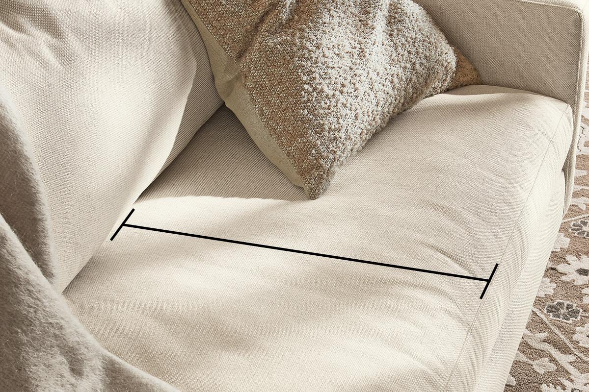 Close-up of a light fabric sofa with measurement line indicating seat depth of the cushion.