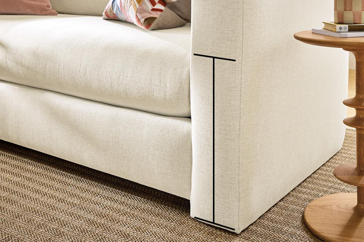 Close-up of sofa arm with measurement line showing seat height beside a wood side table.