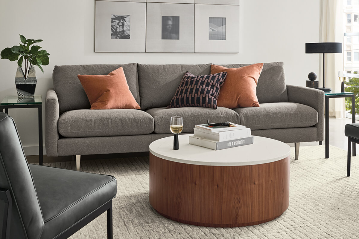 Grey Jasper sofa with Lisbon leather chairs around a round wood coffee table in a living room with framed art, side tables, and rug.