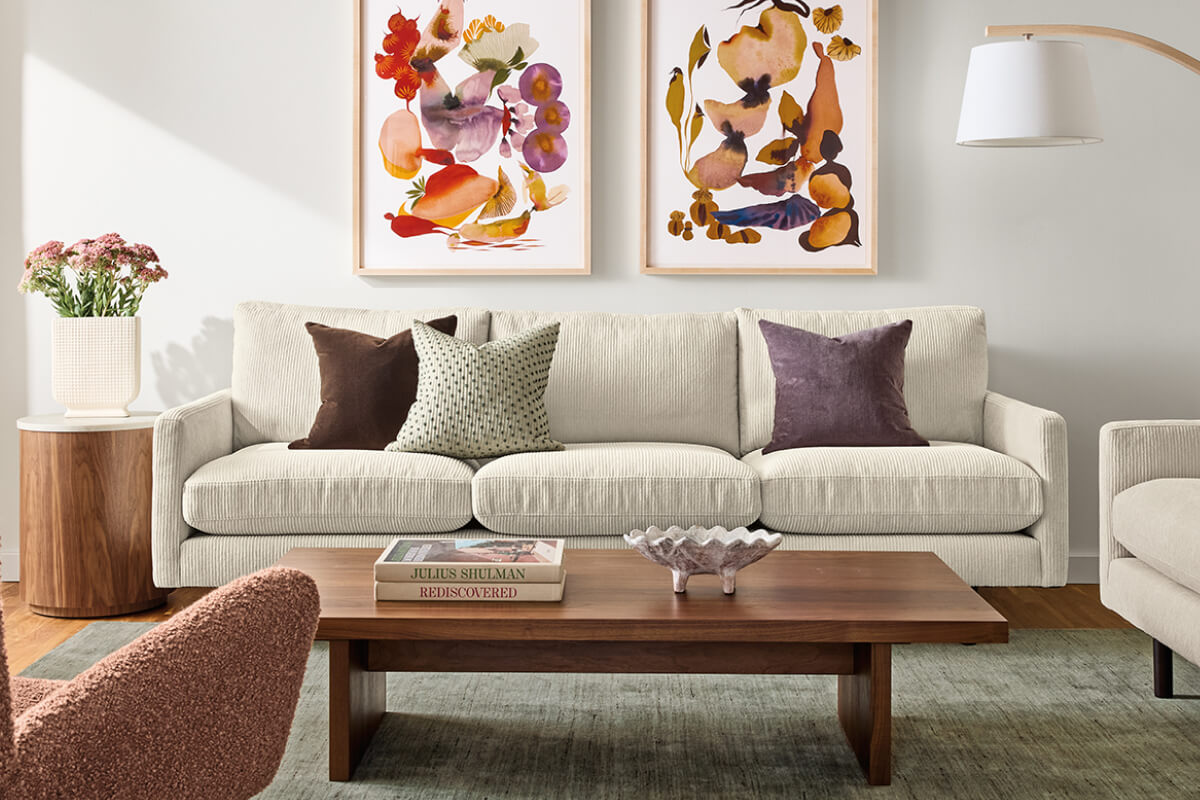 Ivory Jasper sofa styled with throw pillows behind a walnut coffee table in a living room with colorful artwork.