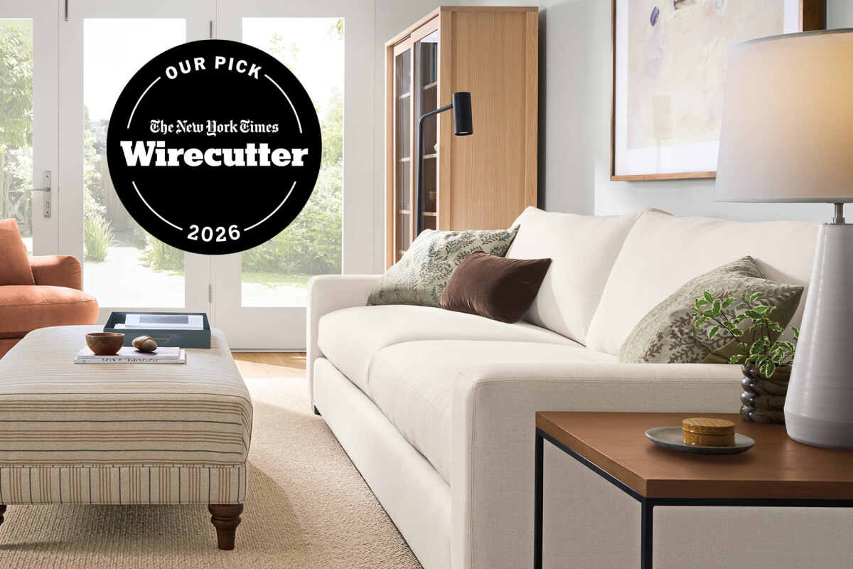 Ivory Metro sofa with green and brown pillows beside a striped ottoman and wood side table, with The New York Times Wirecutter 2026 badge.