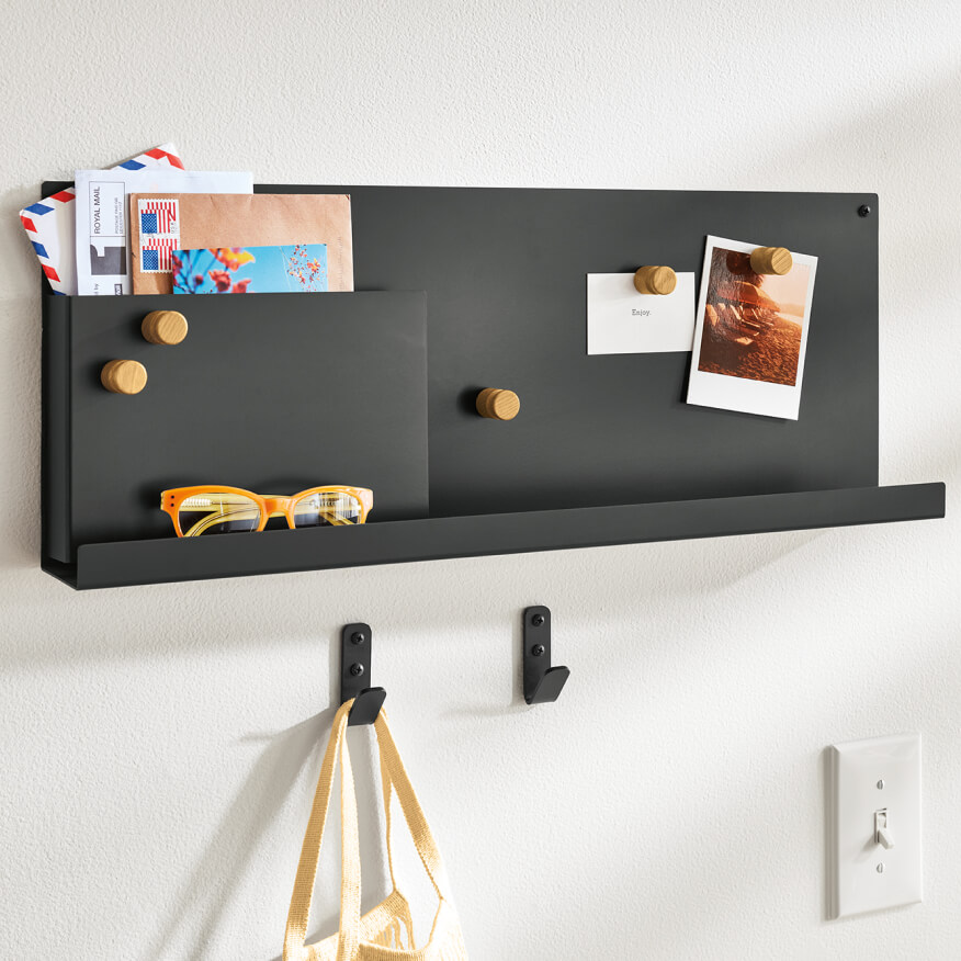 Agenda magnetic board in dark finish with wood magnets, holding mail, photos, and glasses on a wall.