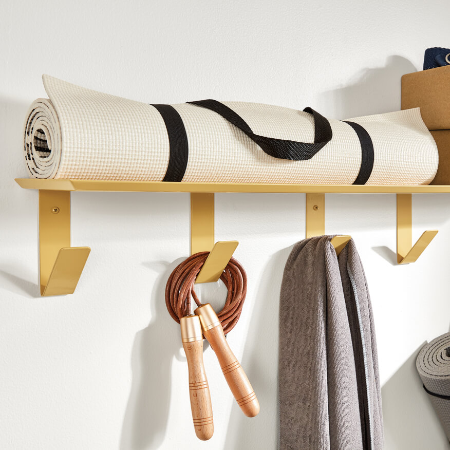 Yellow Bend wall hooks and shelf storing rolled mat, with a rope and towel hanging on hooks.
