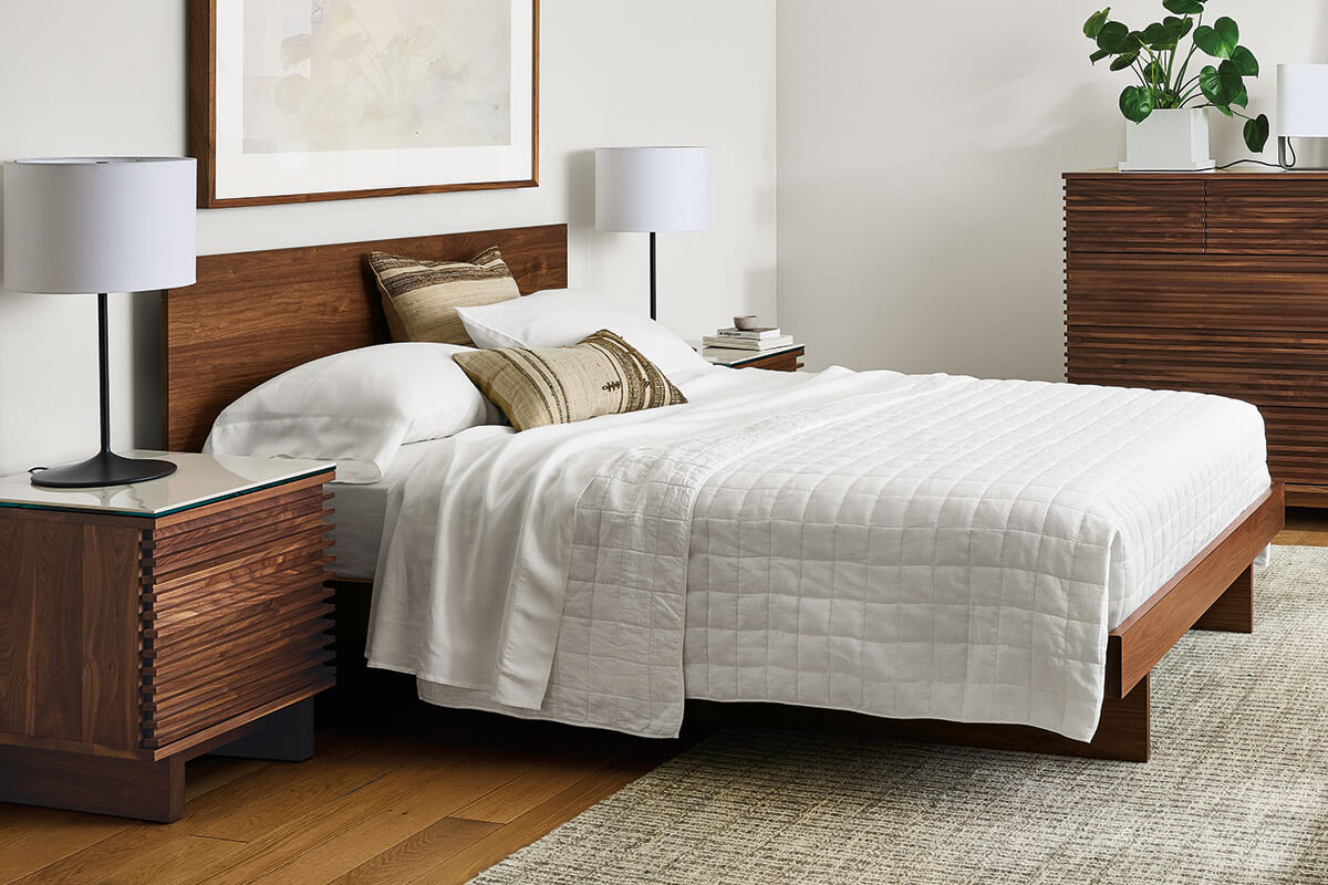 Anton bed with wood frame and white bedding, paired with Coles dresser and matching nightstand.