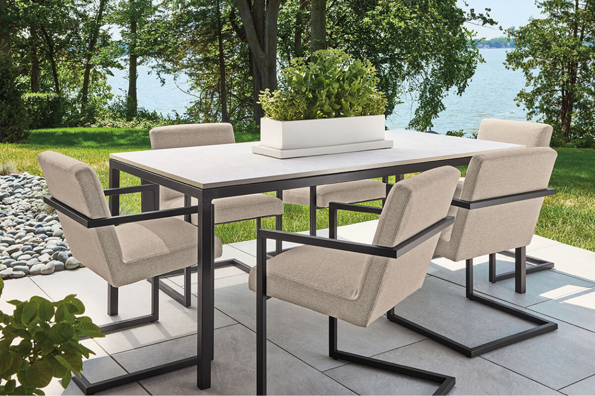 Parsons table with light top and black frame, paired with Finn chairs and planter centerpiece outdoors.