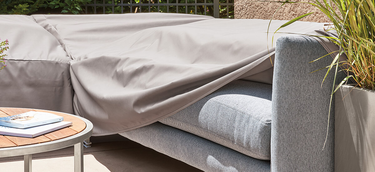 Couch on a patio partially covered by an outdoor furniture cover.
