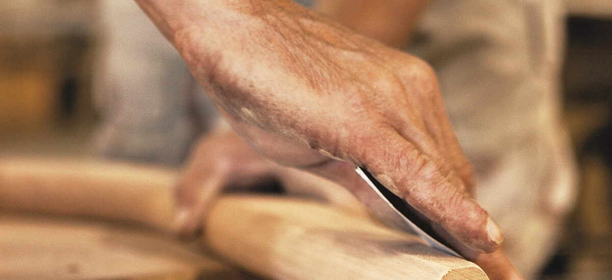 Closeup of a craftsperson's hands sanding a piece of wood.