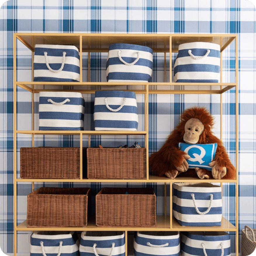 Yellow Foshay bookcase with cubbies holding striped bins, baskets and a stuffed toy.