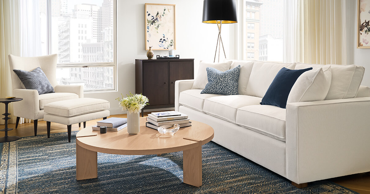 Anza rug in deep blue tones beneath a white sofa, matching lounge chair and round wood coffee table.