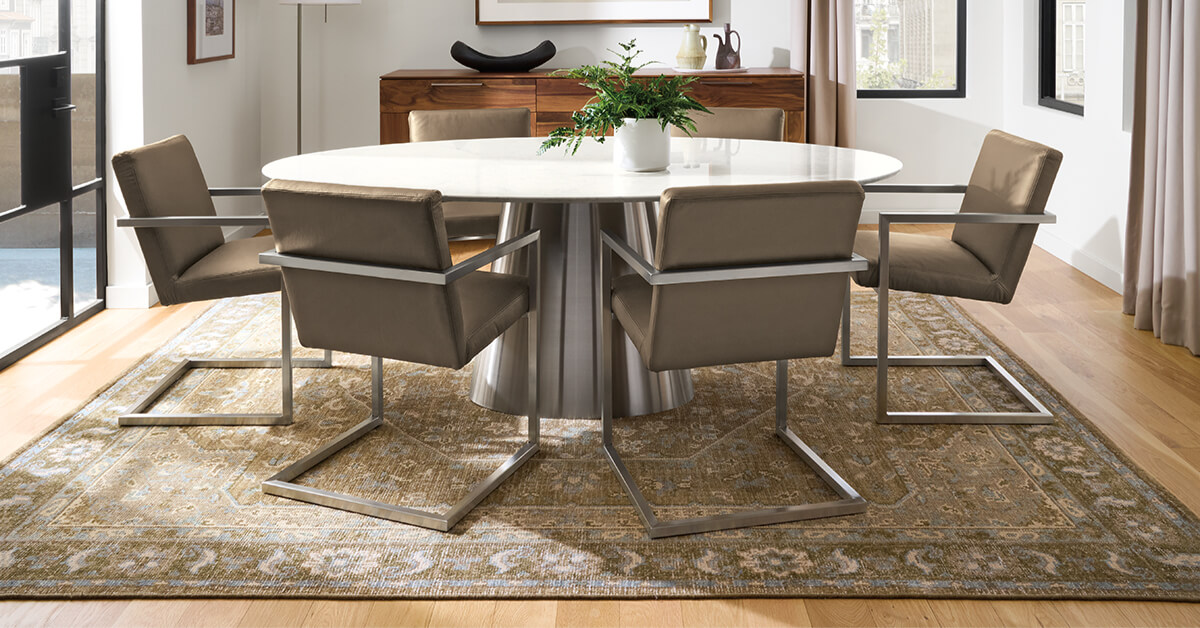 Veda rug in warm beige tones beneath a round dining table and six cantilever dining chairs.