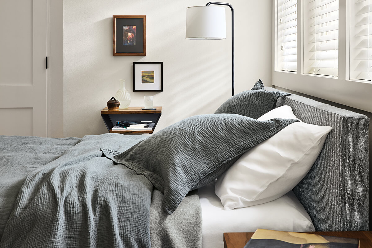 Wyatt upholstered bed with textured grey bedding paired with a black Layne floor lamp and floating nightstand.