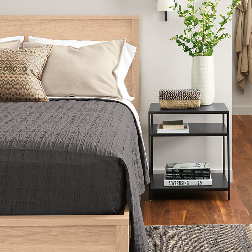 Black Slim end table paired with the Emerson bed, featuring open shelving and decorative bedroom accents.