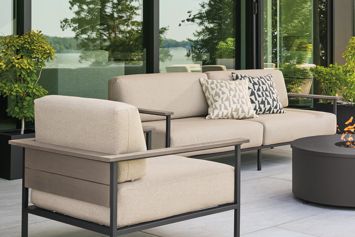 Marin outdoor sofa and lounge chair with light upholstery and metal frame, arranged around a fire table.