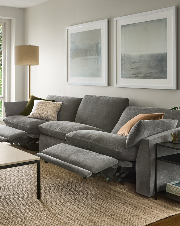 Grey Weber reclining sofa with adjustable footrests, styled with accent pillows beneath framed artwork.