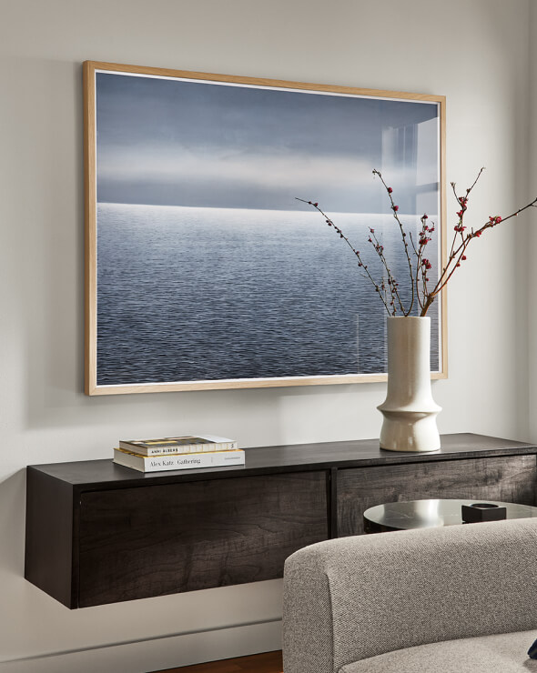 Framed Murray wall art featuring a waterscape photograph, hung above a floating wood cabinet.