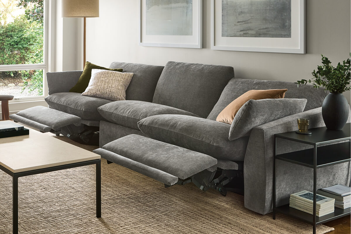 Weber reclining sofa in grey upholstery with extended footrests, accent pillows, and a side table in a living room.