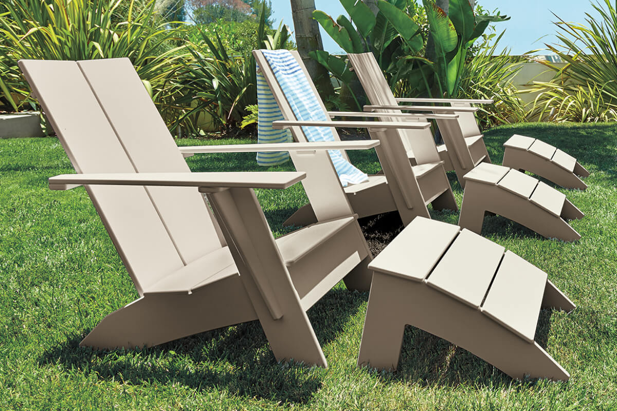Emmet lounge chairs and ottomans grouped outdoors on green grass, with striped towels draped over chair backs.