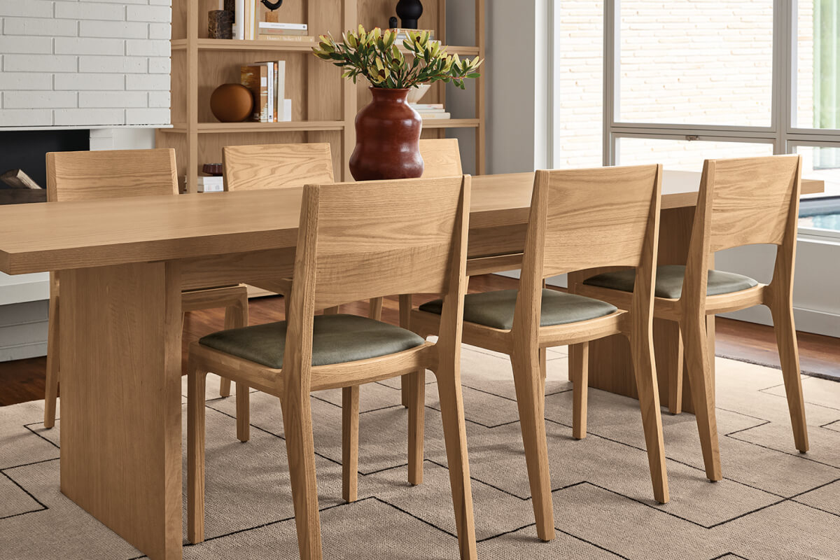 Corbett dining table paired with six Haven dining chairs in oak with upholstered seats, styled with a ceramic vase.