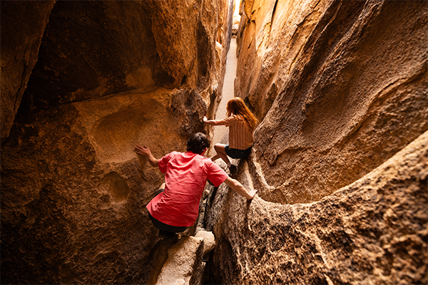 Two people crawling through the cave