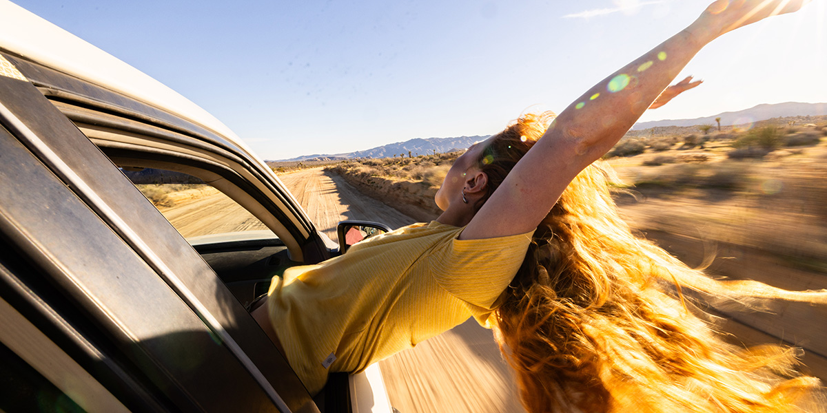 Photo of a woman leaning out a car window.