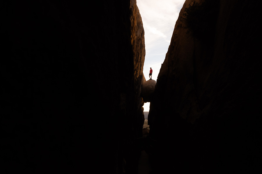 Man standing on a boulder floating between two rocks.